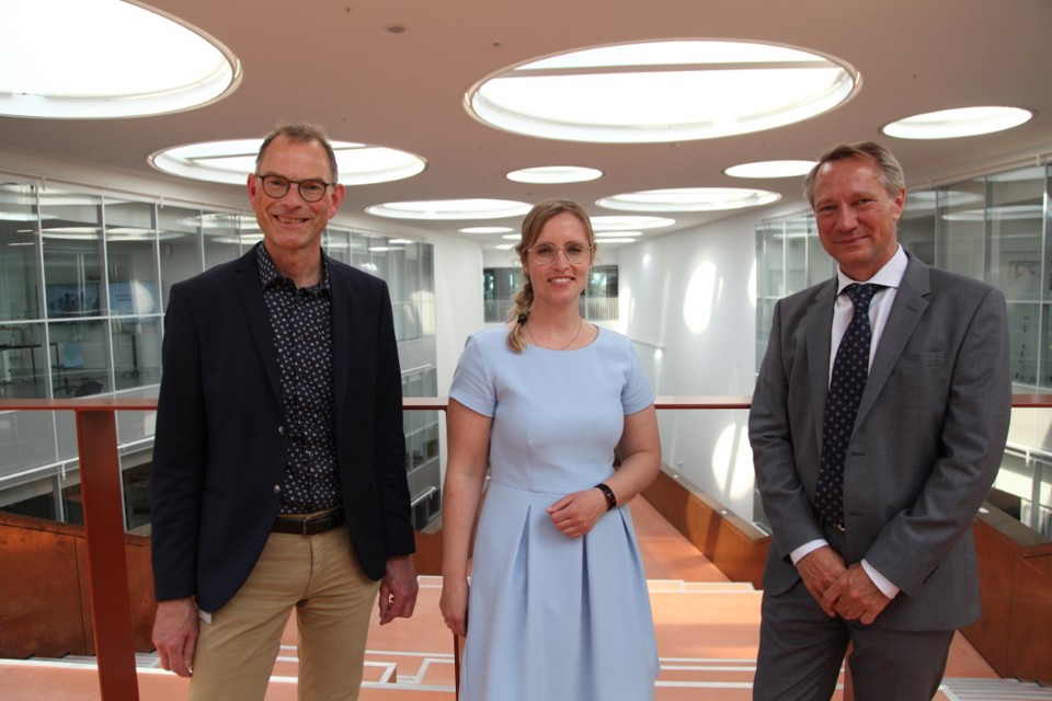 Three people, two men and a woman, smile at the camera